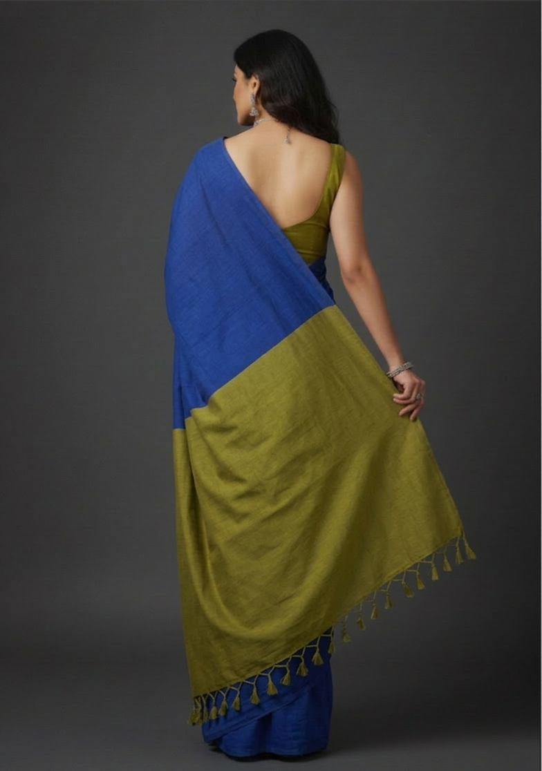 Woman wearing a blue and green saree against a gray background