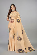 Woman wearing a beige saree with black floral patterns.