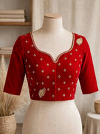 A red three-quarter sleeve blouse displayed on a cream dress form, shown from both front and back views side by side. The blouse features gold embroidery, a scalloped V-neckline on the front, and small gold motifs throughout, with a gold leaf design on the back.